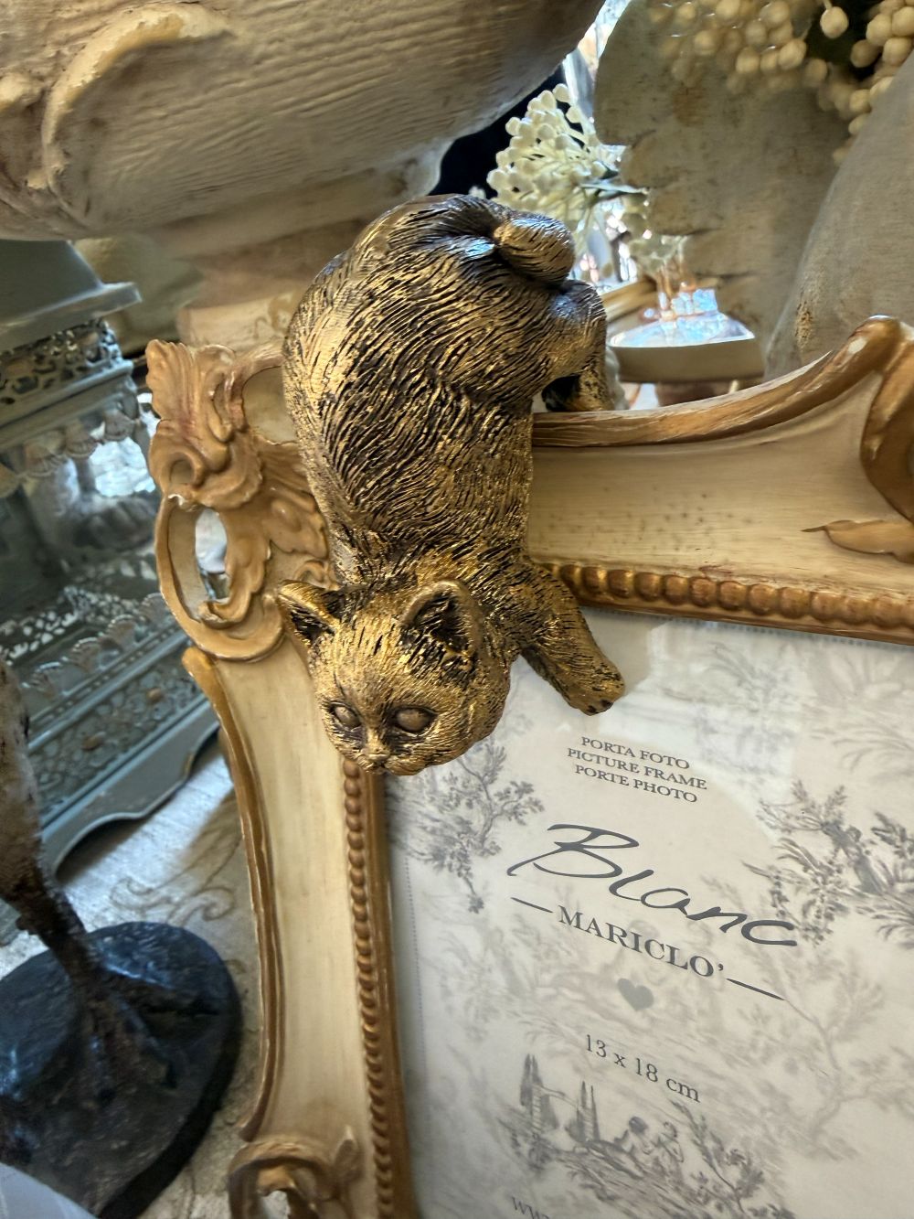 Chat grimpeur décoratif or vieilli accroché à un rebord dans une ambiance de décoration shabby chic romantique et poétique