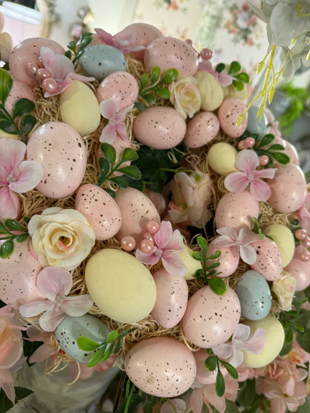 Couronne de Pâques décorative avec œufs pastel roses jaunes et bleus, fleurs et feuillage, style shabby chic romantique et printanier