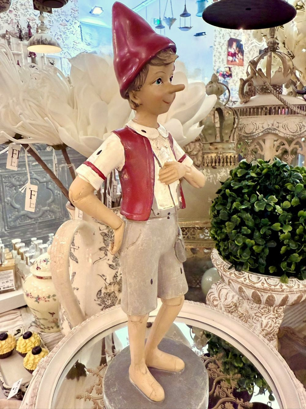 Figurine déco de Pinocchio en posture de marche, couleurs rouge bordeaux, beige et gris clair, style poétique et shabby chic, compagnon de balade au charme romantique