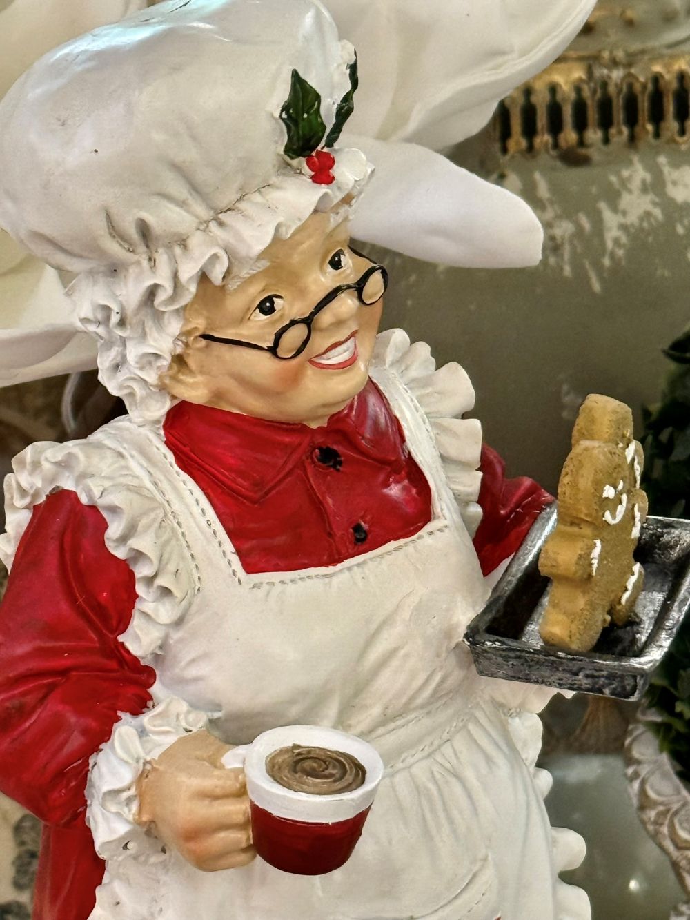 Figurine décorative de 30 cm représentant la Mère Noël en tenue de pâtissière rouge et blanche, tenant une tasse et un biscuit pain d’épices, style vintage et féérique