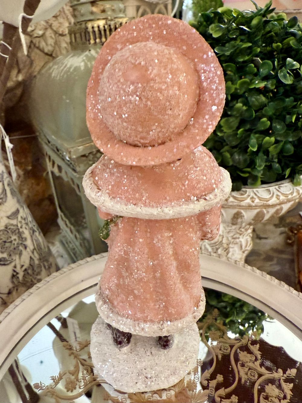 Figurine de Noël représentant une petite chanteuse en manteau rose et bonnet assorti, dans un style victorien romantique, sur fond de décoration shabby chic