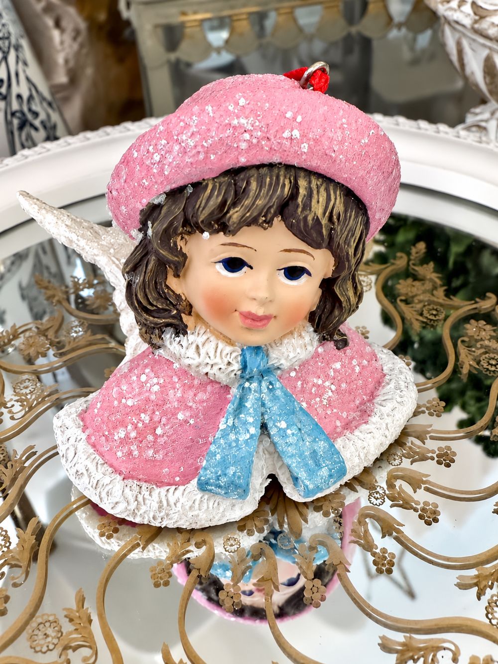 Vue de face de la figurine Ange Poupée Victorienne, avec sa cape rose et son ruban bleu pailletés.
