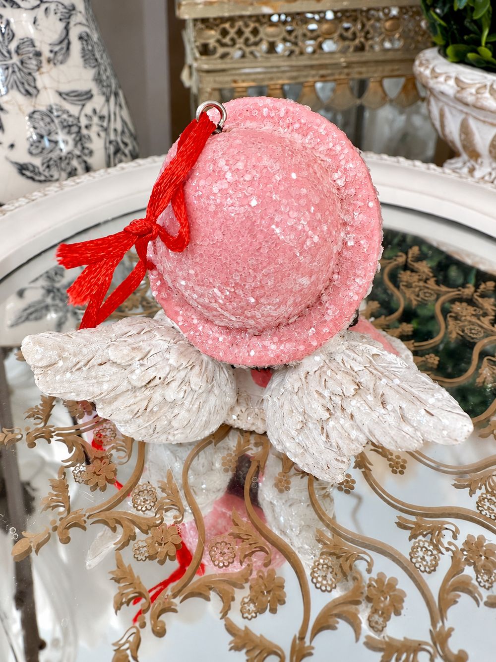 Vue arrière de la suspension ange, avec son bonnet rose pailleté, ses ailes blanches et son cordon rouge.