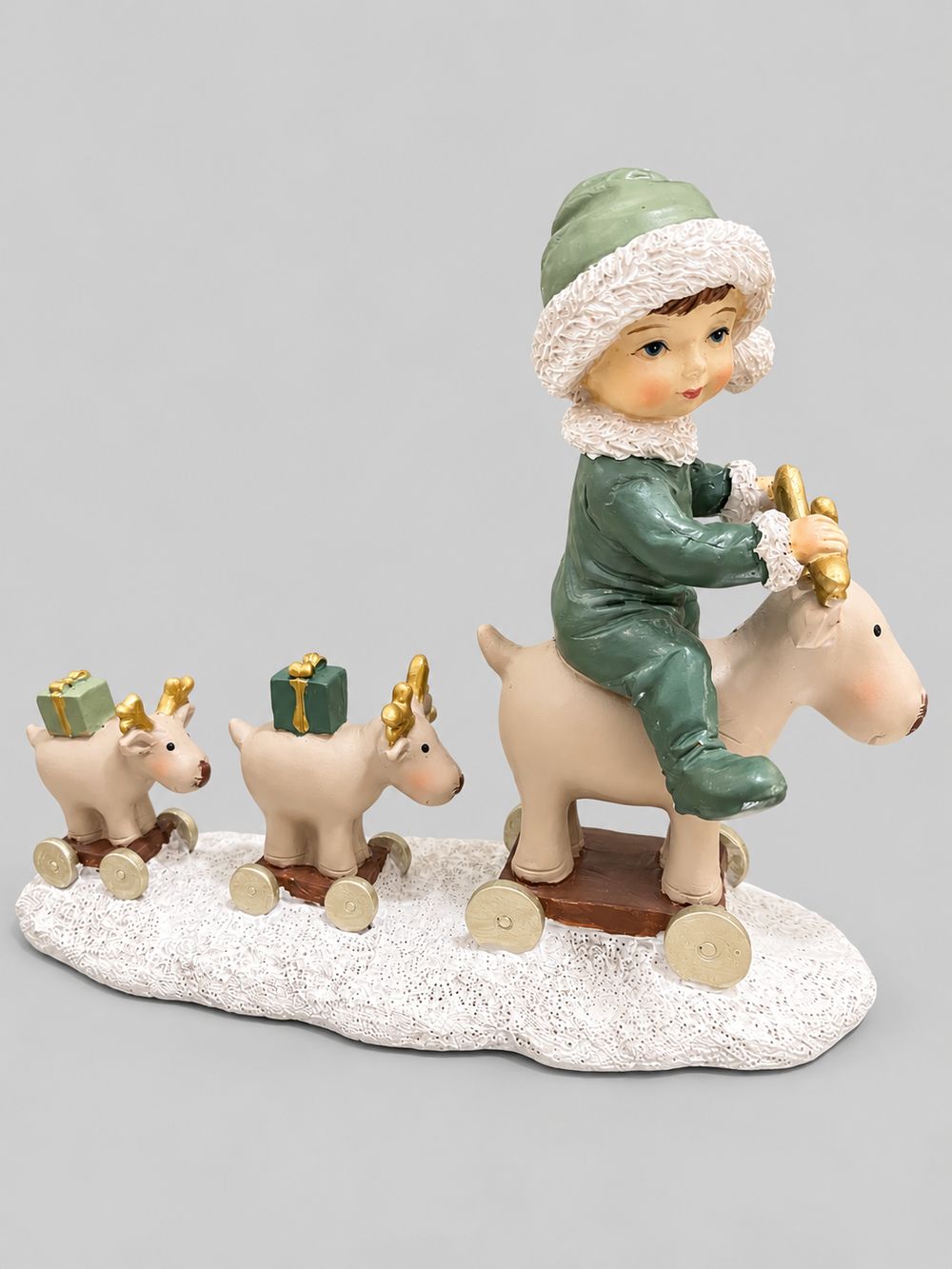 Statuette Balade des Petits Rennes en résine, avec un enfant vêtu de vert et trois rennes sur un socle enneigé, sur fond gris clair.