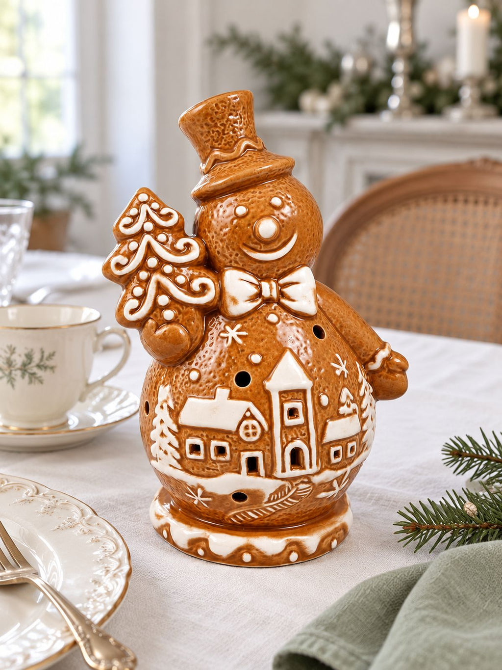 Bonhomme de neige Biscuit sur une table de Noël en lin blanc, accompagné de vaisselle ancienne et d’une serviette vert sauge.