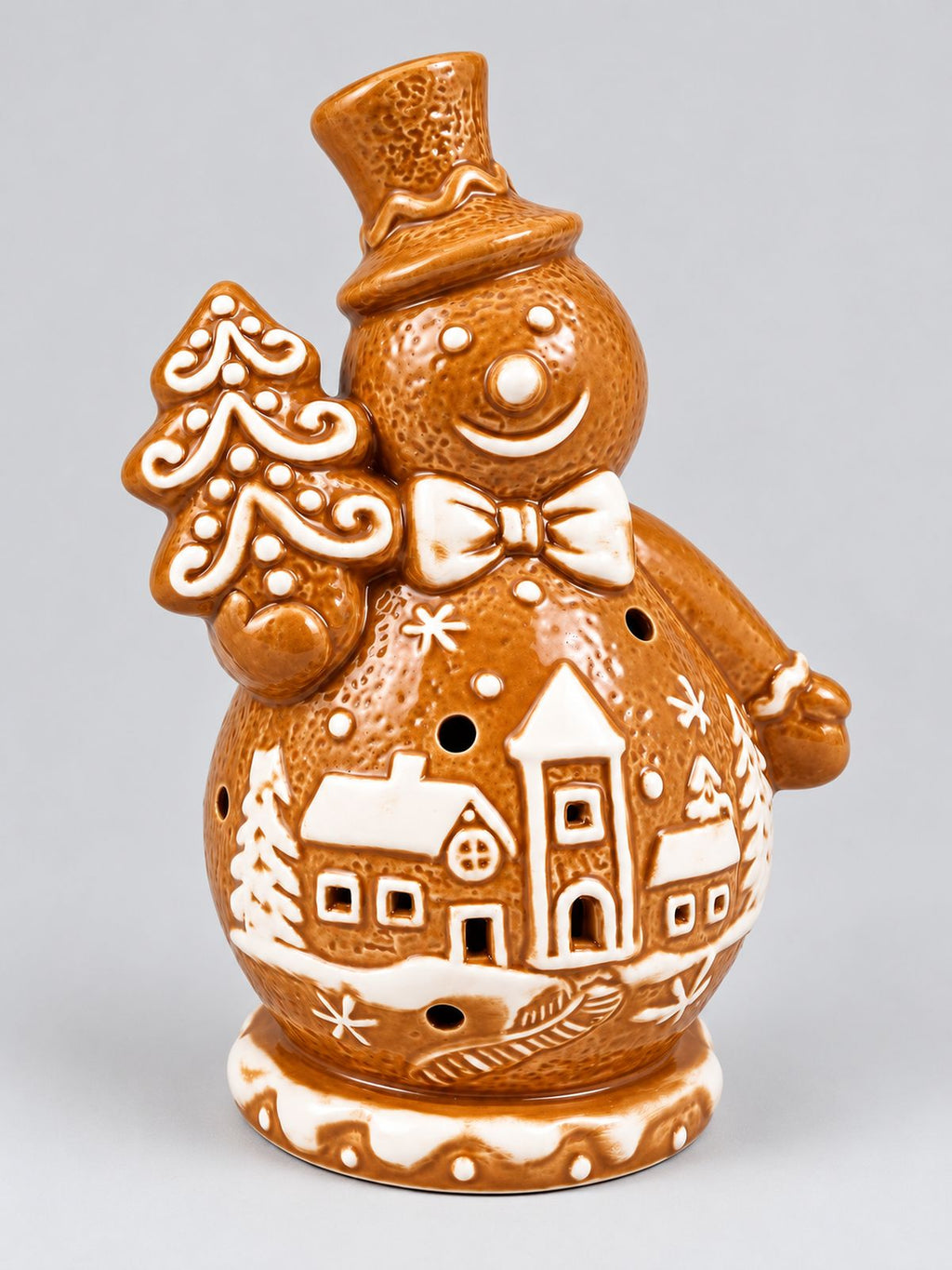 Bonhomme de neige en porcelaine façon biscuit, caramel et blanc, tenant un sapin et décoré d’un village enneigé, sur fond gris clair.