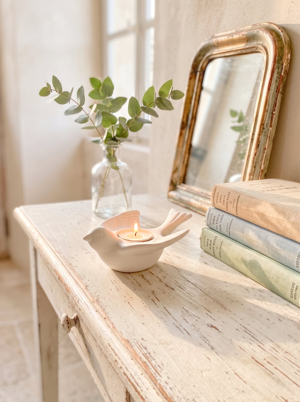 Bougeoir en biscuit blanc en forme d'hirondelle posé sur une nappe brodée, style romantique