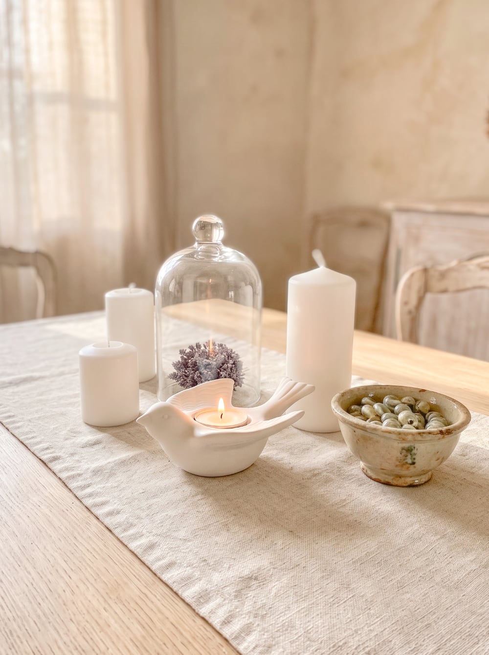 Bougeoir en biscuit blanc en forme d'hirondelle posé sur une nappe brodée, style romantique