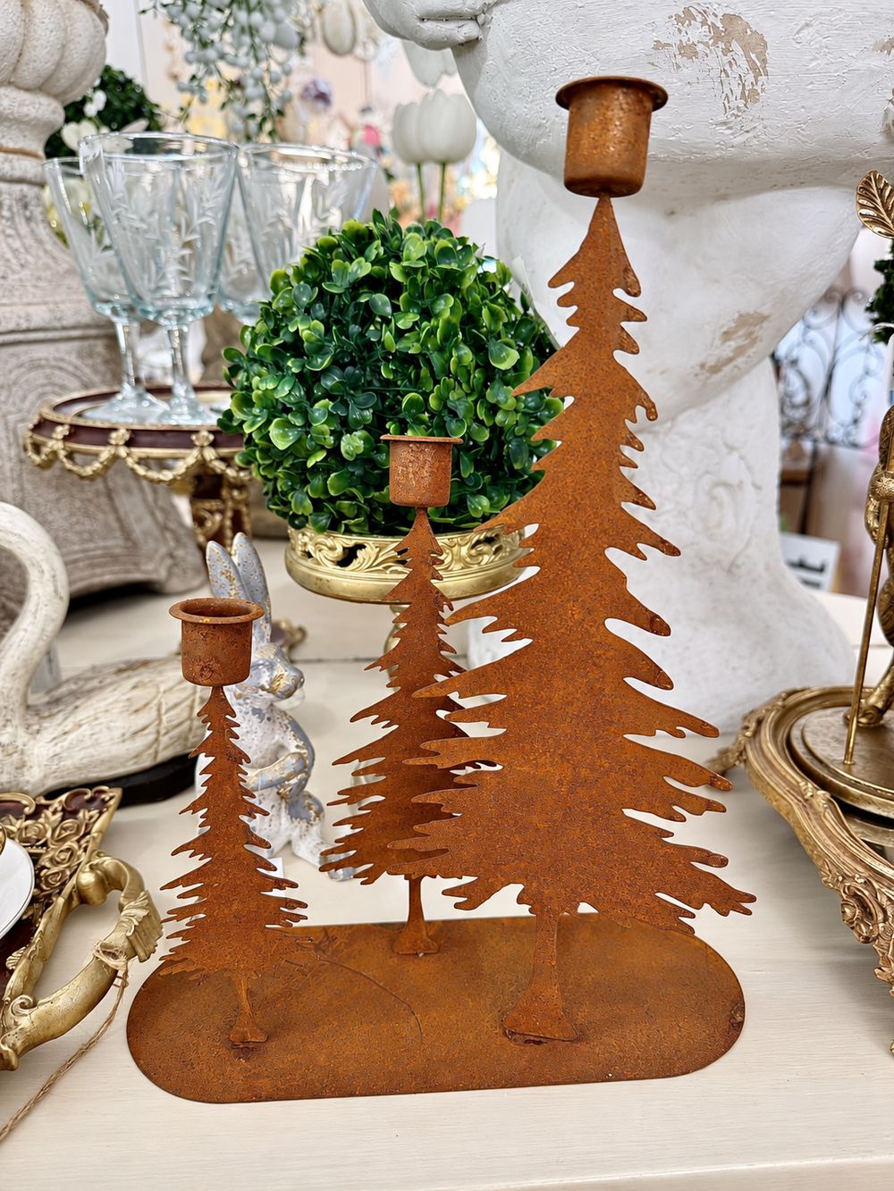 Bougeoir à trois sapins en métal rouille, vu de face dans la boutique.