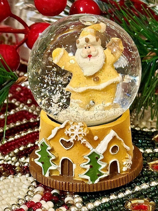 Boule à neige miniature avec Père Noël doré et base en forme de maison pain d’épices, déco de Noël romantique et féérique aux tons dorés, blancs et verts
