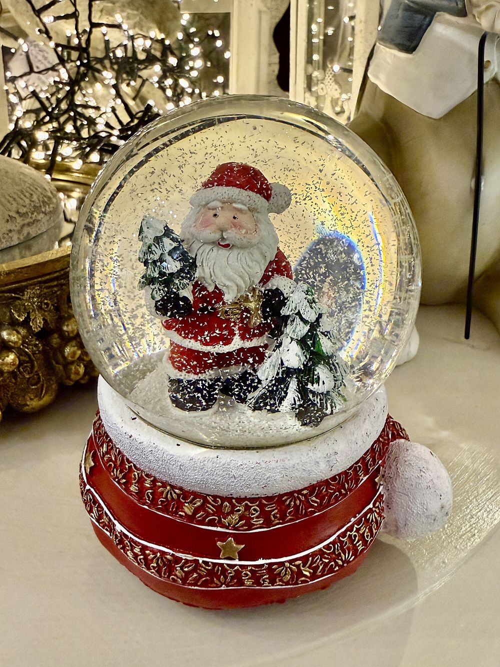Boule à neige Père Noël musical rouge et doré avec sapins enneigés, accessoire de décoration féérique et de charme pour Noël