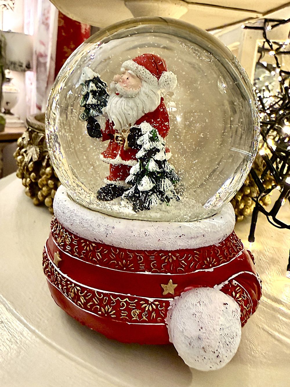 Boule à neige Père Noël musical rouge et doré avec sapins enneigés, accessoire de décoration féérique et de charme pour Noël