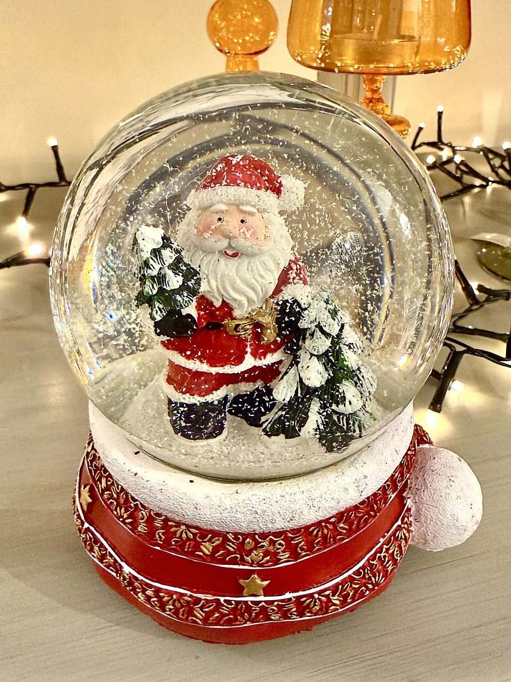 Boule à neige Père Noël musical rouge et doré avec sapins enneigés, accessoire de décoration féérique et de charme pour Noël