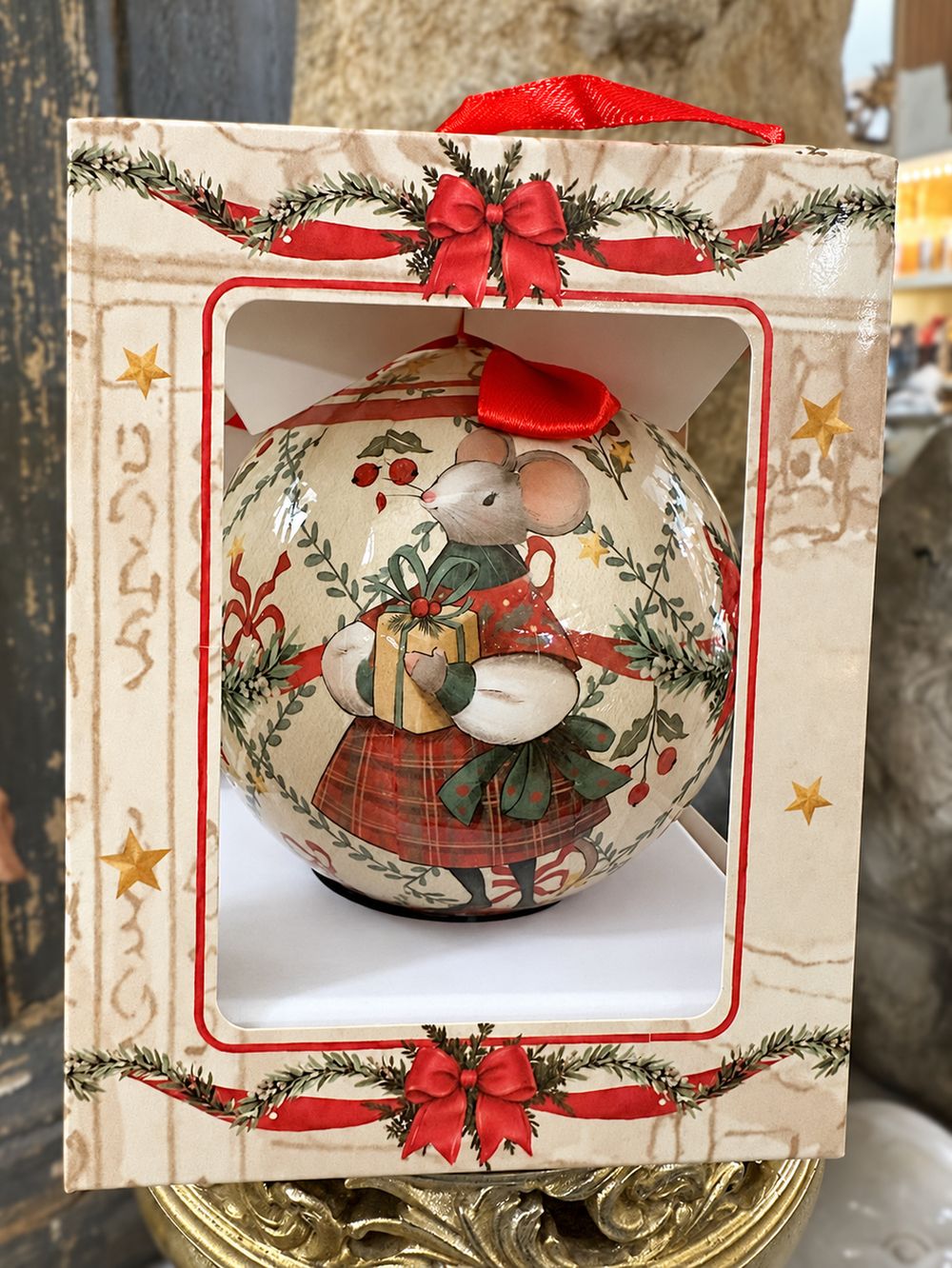 Boule de Noël Souris dans son coffret décoré de nœuds rouges et d’étoiles dorées.