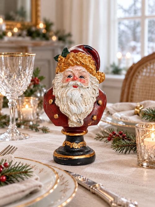Buste du Père Noël sur une table de fête en lin écru, entouré de porcelaine ancienne, de verres à pied et de branches de sapin.