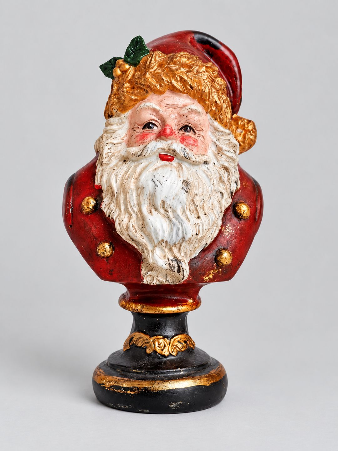 Buste du Père Noël rouge, blanc et doré sur socle noir, présenté sur fond gris clair.