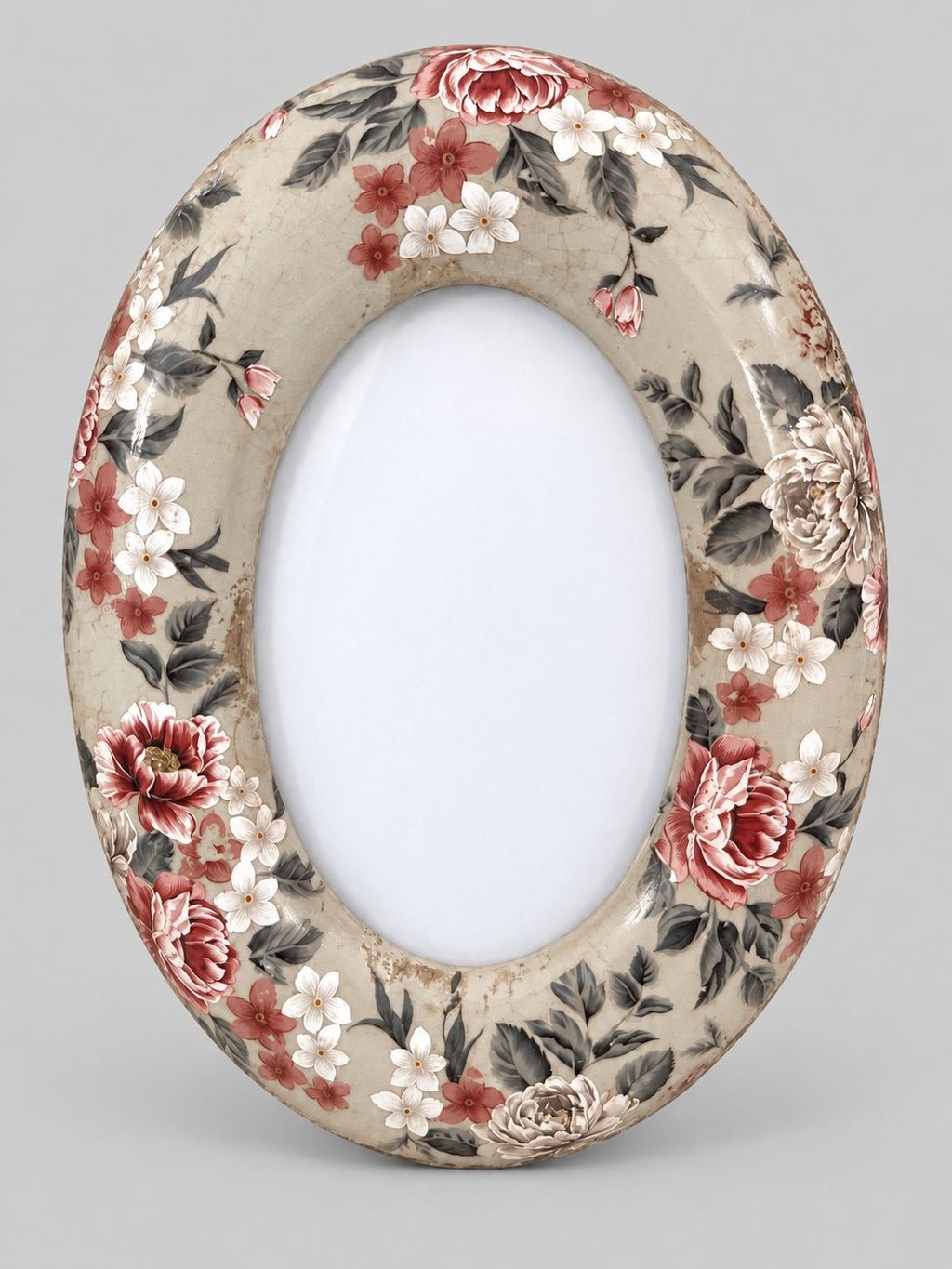 Cadre photo ovale en céramique beige craquelée, à motifs floraux rouges et blancs, sur fond gris clair.
