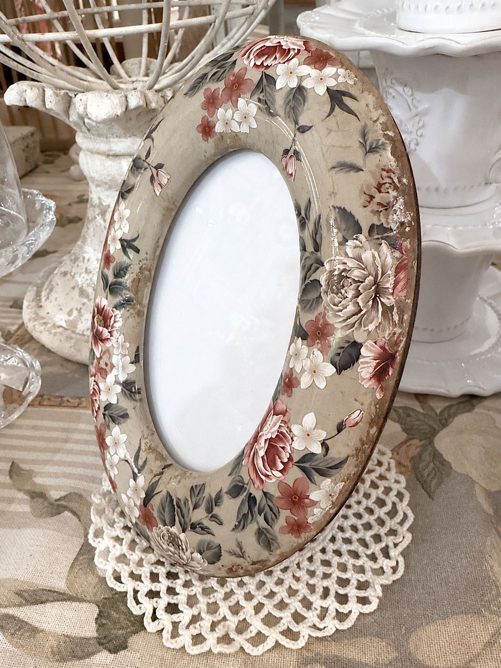 Cadre photo bucolique en céramique vu de trois quarts, montrant son décor floral et sa forme bombée.