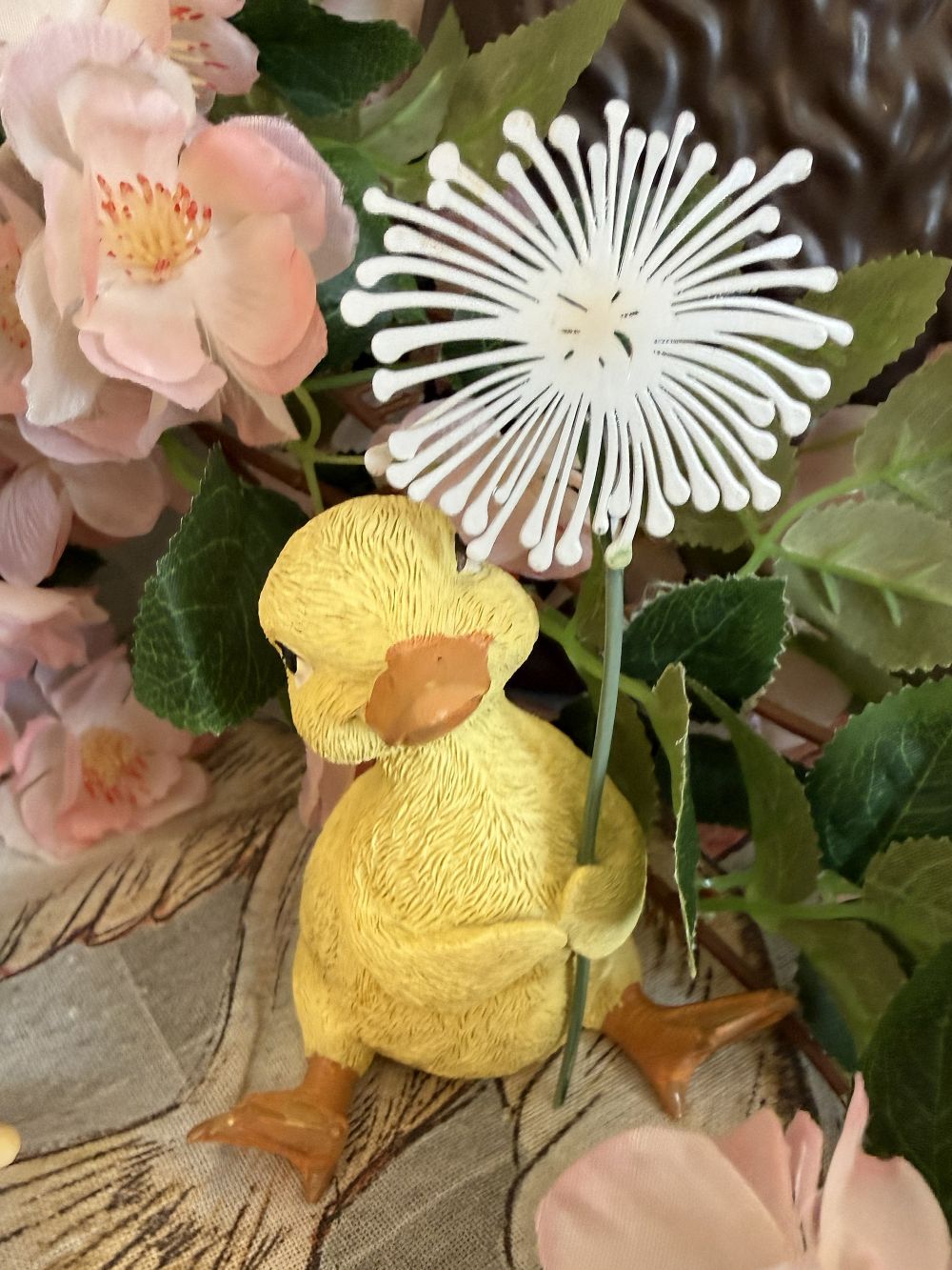 Caneton décoratif jaune tenant une fleur blanche, figurine au charme printanier dans un univers romantique, shabby chic et poétique, idéale pour une décoration de charme douce et féérique