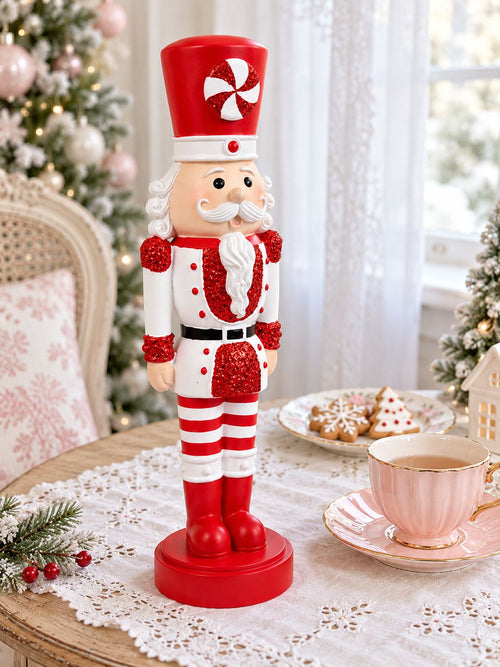 Casse-Noisette Candy Pailleté sur une table à thé, près d’une tasse rose et de biscuits de Noël.
