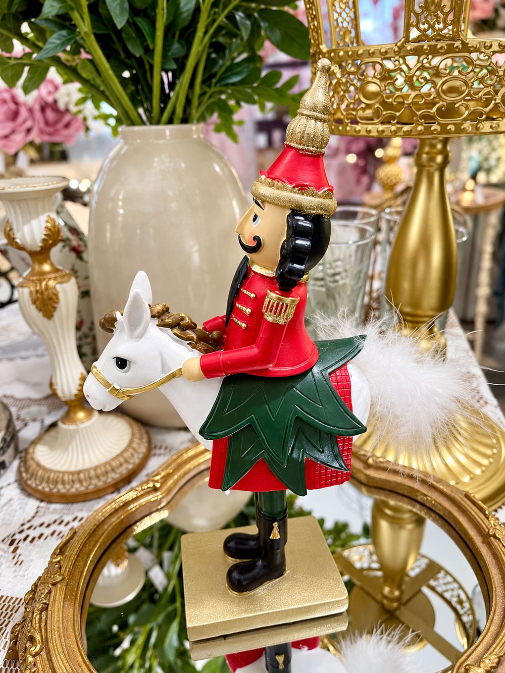 Casse-Noisette Cavalier Royal vu de profil, avec tête de cheval blanche et ornements verts et dorés, sur un plateau miroir.
