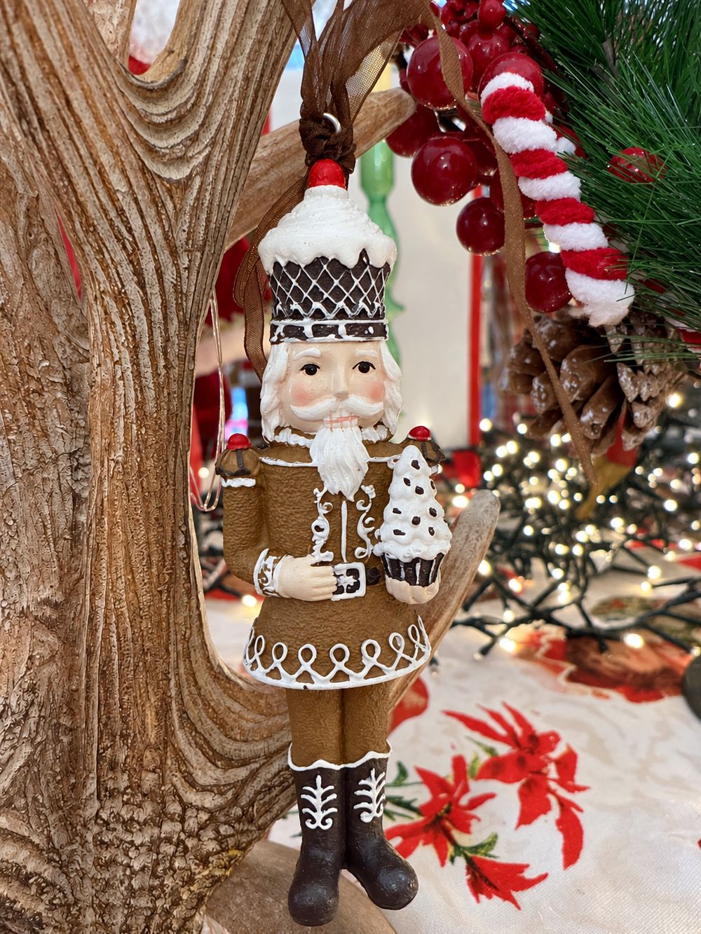 Casse-noisette Cupcake vu de face, suspendu à un arbre décoratif en bois dans la boutique.