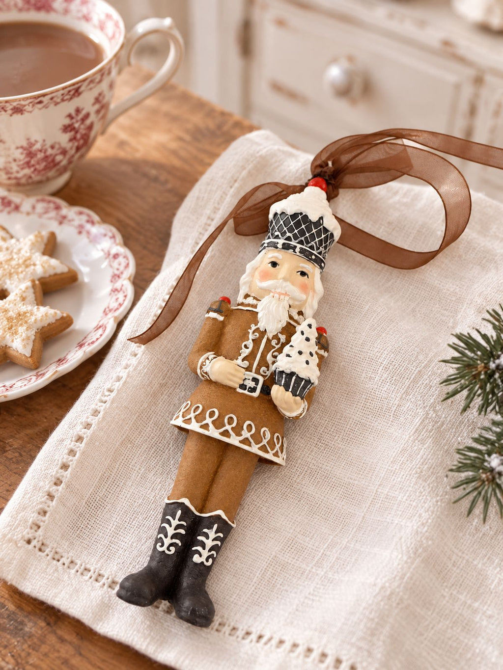 Casse-noisette Cupcake posé sur une serviette claire, près d’une tasse et de biscuits étoilés pour un goûter de Noël.