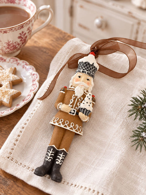 Casse-noisette Cupcake posé sur une serviette claire, près d’une tasse et de biscuits étoilés pour un goûter de Noël.