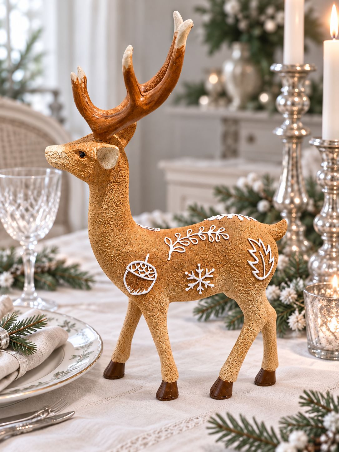 Cerf décoratif Le Prince des Forêts sur une table de fête, avec vaisselle délicate, bougeoirs argentés et branches de sapin.