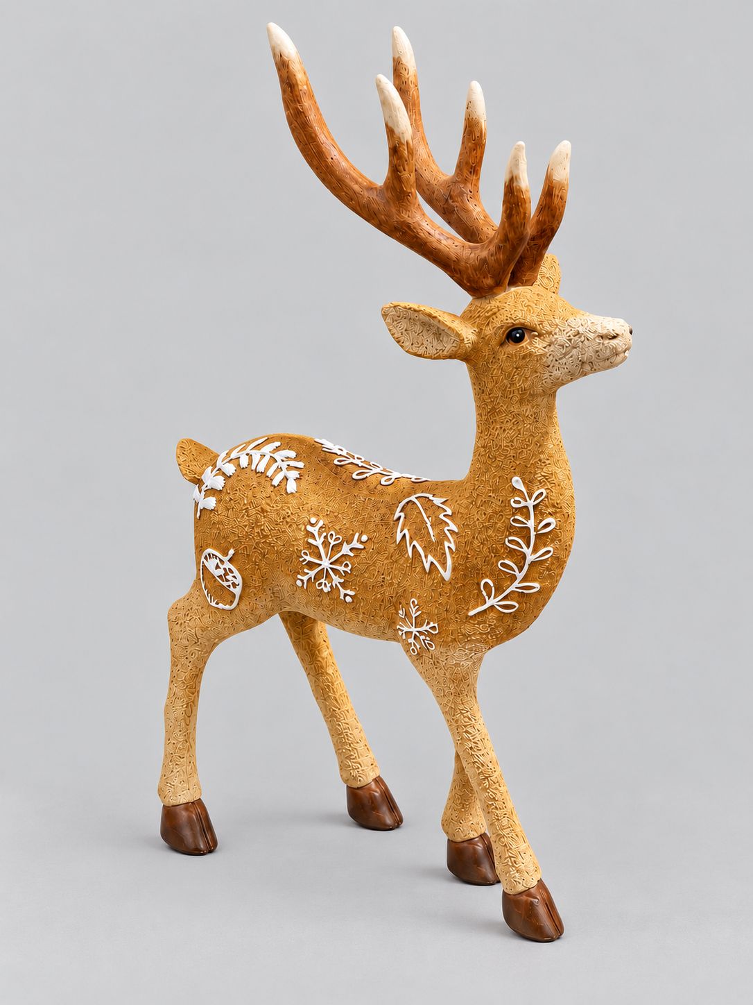 Statuette de cerf Le Prince des Forêts, couleur ocre et ornements blancs, sur fond gris clair.
