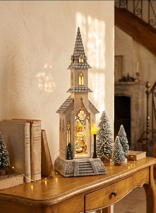 Chapelle de Noël lumineuse blanc ivoire avec clocher gothique, scène de la Nativité sous paillettes scintillantes, décoration féérique musicale pour intérieur de charme