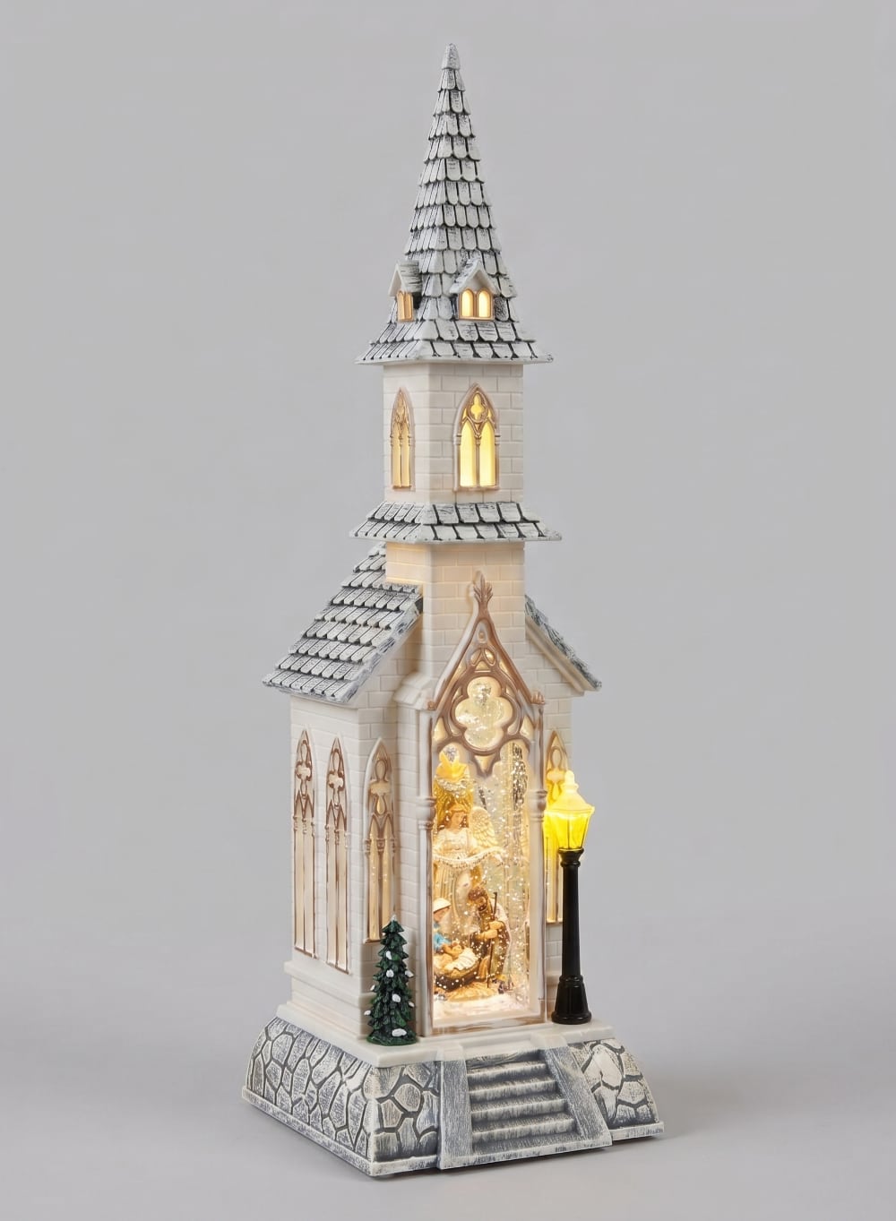 Chapelle de Noël lumineuse blanc ivoire avec clocher gothique, scène de la Nativité sous paillettes scintillantes, décoration féérique musicale pour intérieur de charme