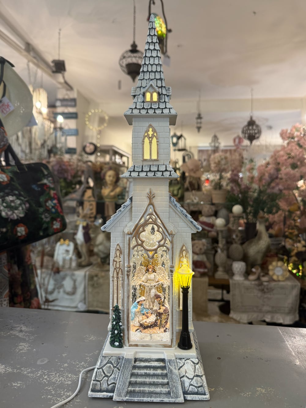 Chapelle de Noël lumineuse blanc ivoire avec clocher gothique, scène de la Nativité sous paillettes scintillantes, décoration féérique musicale pour intérieur de charme