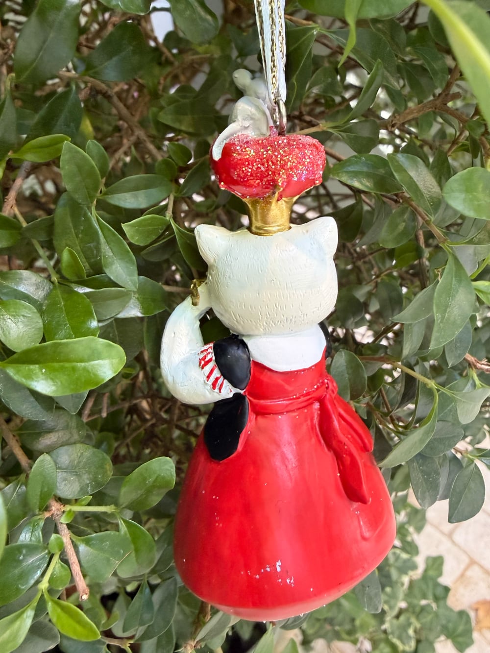Chat d'Alice suspendu portant une robe rouge avec cœurs, une couronne dorée surmontée d'une souris et un face-à-main en forme de cœur, décoration féérique à suspendre