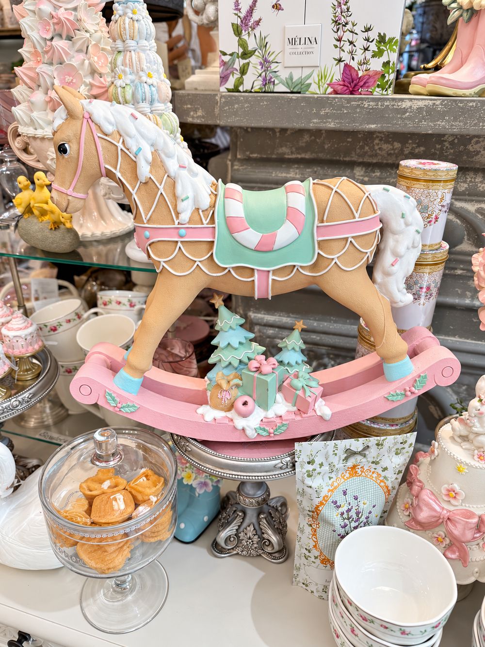 Grand cheval à bascule décoratif aux tons rose pastel, vert menthe, blanc et caramel, dans un style féérique et gourmand pour une décoration de Noël poétique.
