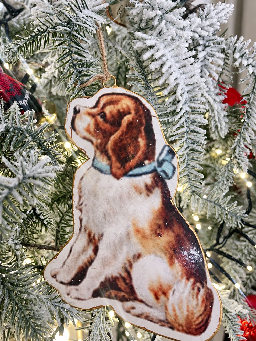 Détail de la suspension en métal chien victorien et de sa bordure dorée dans un sapin givré.