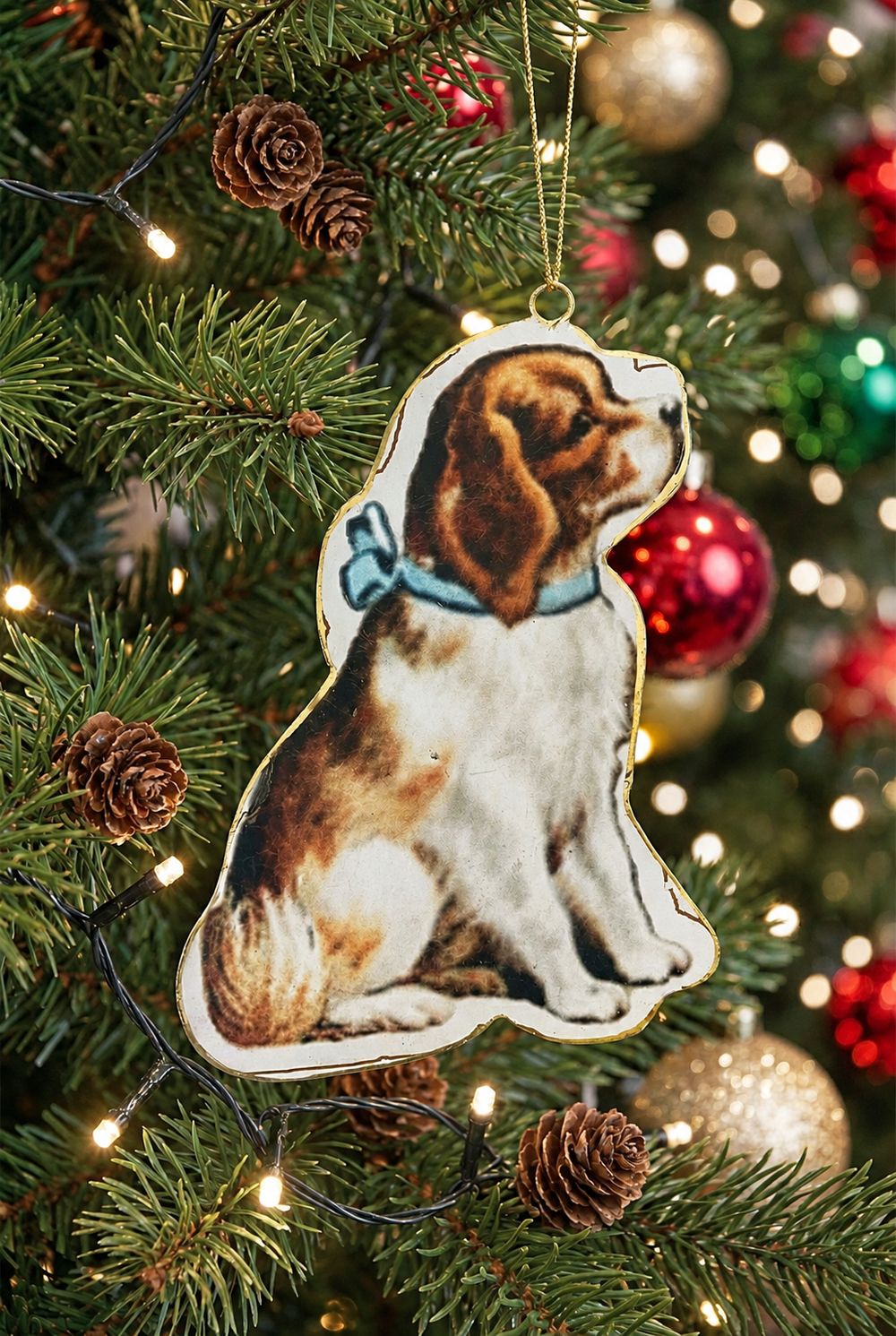 Suspension chien victorien accrochée dans un sapin avec des boules rouges et dorées.