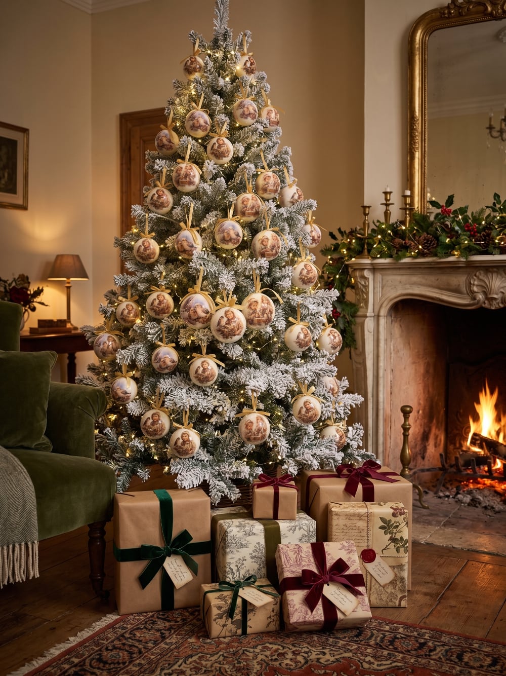 Coffret de boules de Noël décoratives illustrées de scènes d'enfance et de petits oiseaux, dans des tons crème et beige, suspendues sur un sapin enneigé au style romantique et vintage