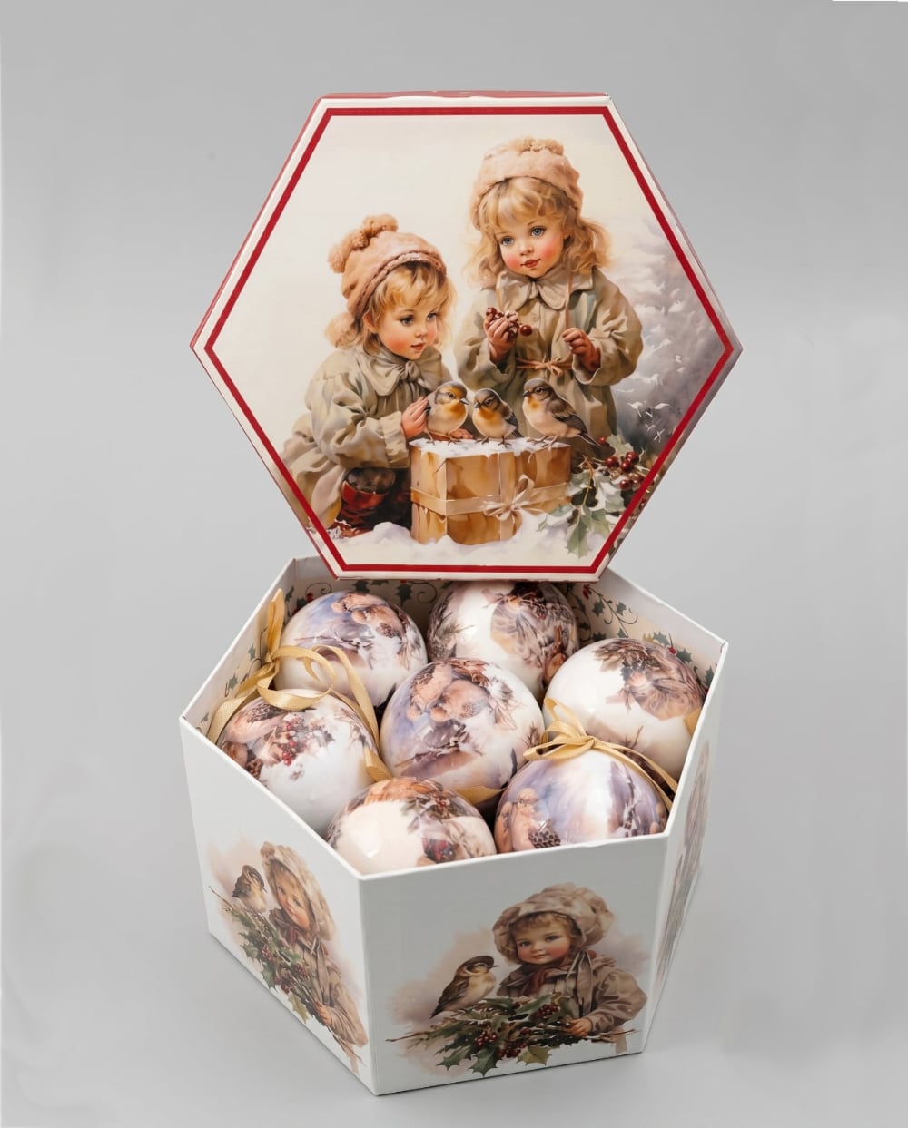 Coffret de boules de Noël décoratives illustrées de scènes d'enfance et de petits oiseaux, dans des tons crème et beige, suspendues sur un sapin enneigé au style romantique et vintage
