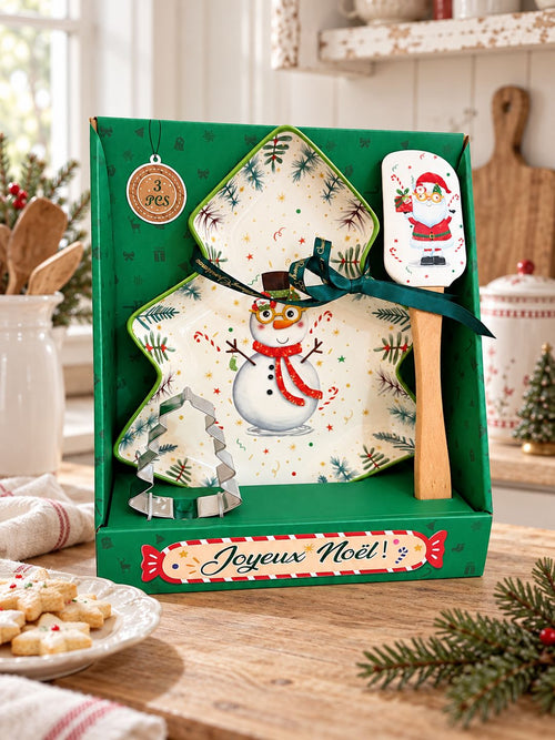 Coffret Snowman de Noël sur un plan de travail en bois, près de sablés dans une cuisine lumineuse.