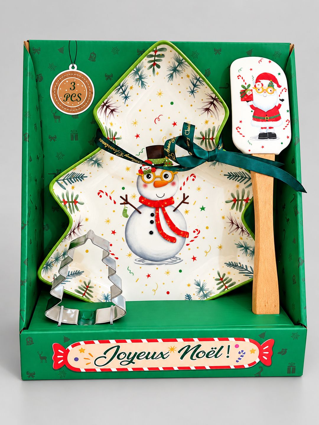 Coffret cadeau Snowman de Noël sur fond gris clair, avec plat sapin, spatule Père Noël et emporte-pièce en métal.