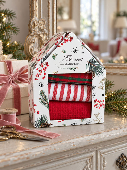 Coffret de torchons de Noël Blanc MariClò sur une console patinée, accompagné d’un cadeau et d’un ruban vieux rose.