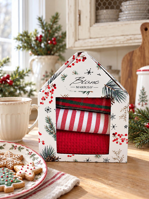 Coffret de torchons de Noël Blanc MariClò sur un plan de travail en bois clair, près d’une tasse et de biscuits décorés.