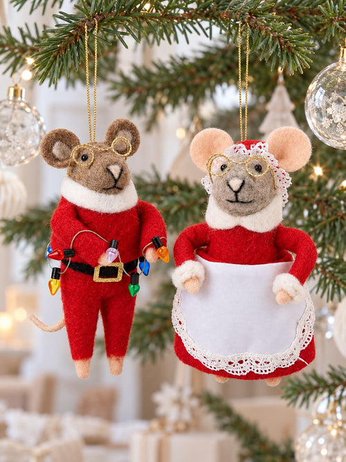 Couple de souris de Noël en feutrine rouge, suspendues par des fils dorés aux branches d’un sapin décoré de boules transparentes.