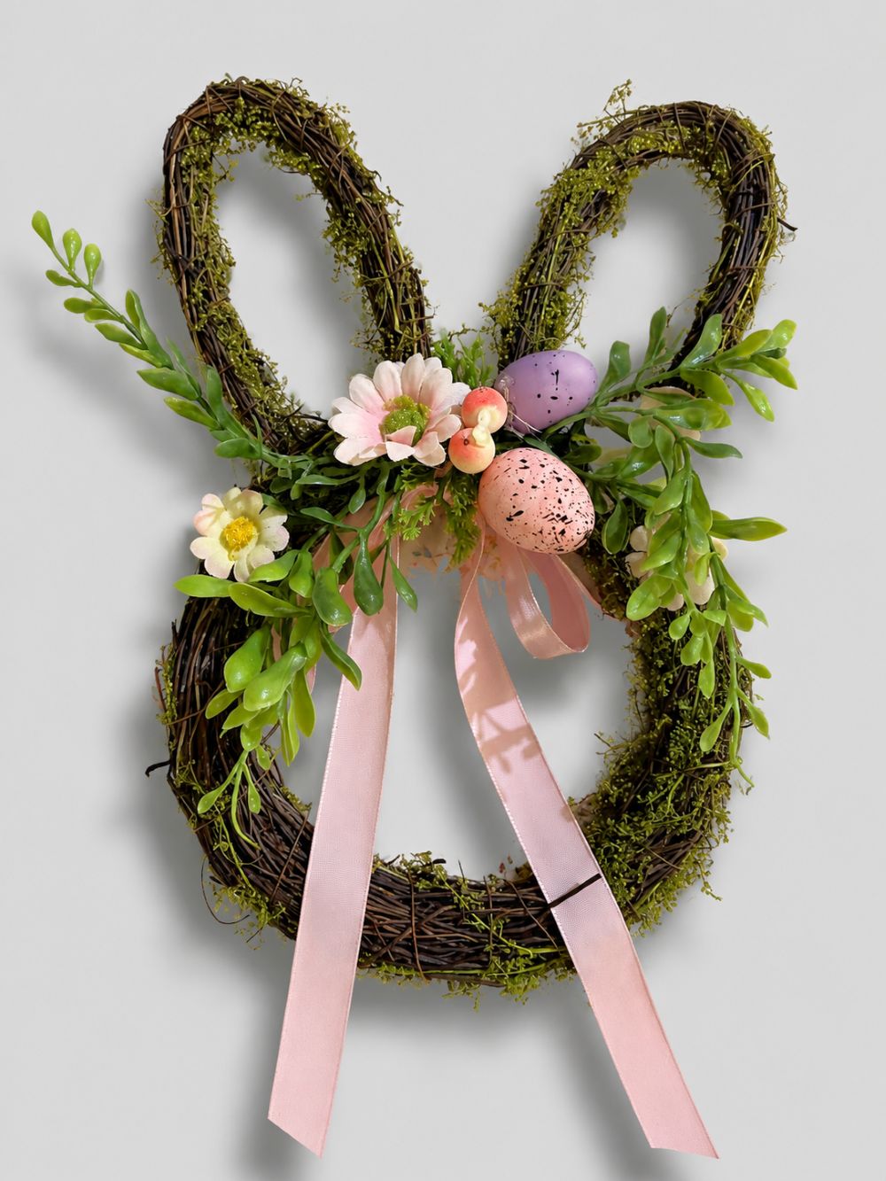 Couronne de Pâques en forme de lapin en osier brun, décorée de feuillage vert, fleurs roses, œufs pastel et rubans, style shabby chic romantique