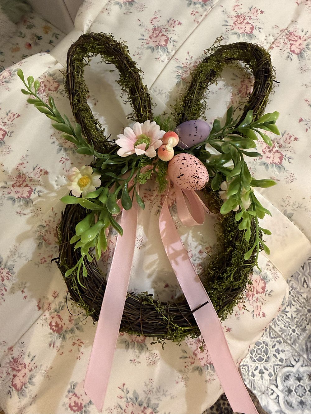 Couronne de Pâques en forme de lapin en osier brun, décorée de feuillage vert, fleurs roses, œufs pastel et rubans, style shabby chic romantique