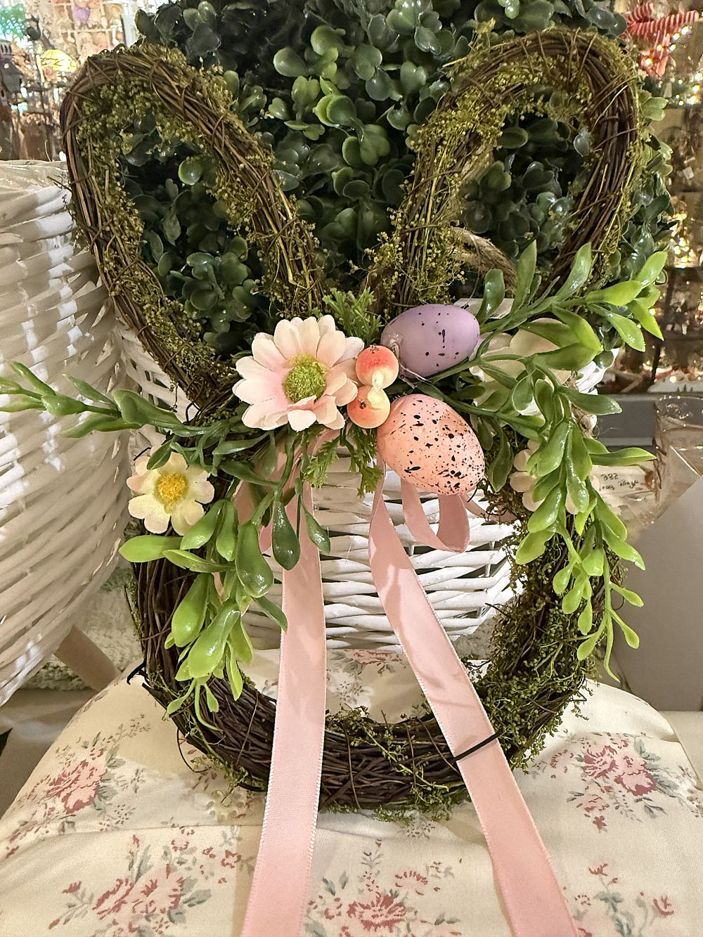 Couronne de Pâques en forme de lapin en osier brun, décorée de feuillage vert, fleurs roses, œufs pastel et rubans, style shabby chic romantique