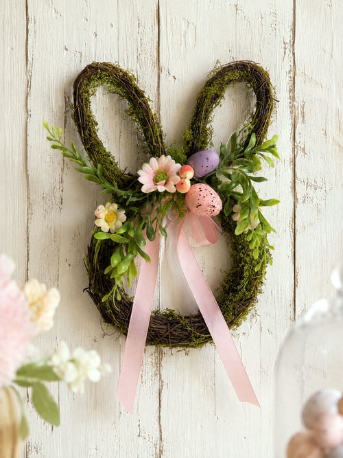 Couronne de Pâques en forme de lapin en osier brun, décorée de feuillage vert, fleurs roses, œufs pastel et rubans, style shabby chic romantique