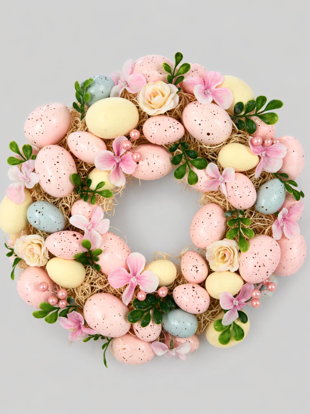 Couronne de Pâques décorative avec œufs pastel roses jaunes et bleus, fleurs et feuillage, style shabby chic romantique et printanier