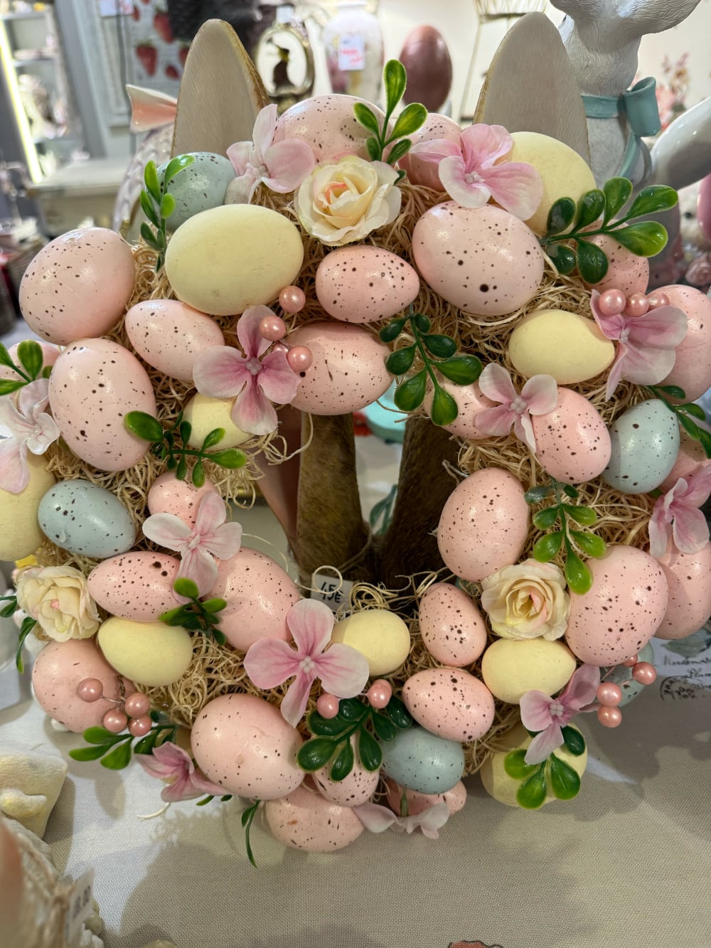 Couronne de Pâques décorative avec œufs pastel roses jaunes et bleus, fleurs et feuillage, style shabby chic romantique et printanier